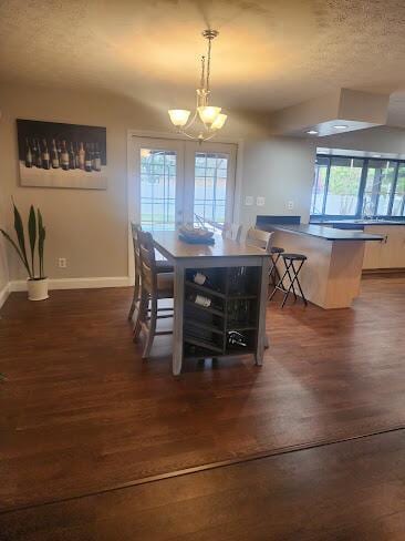 dining space featuring dark wood-type flooring, plenty of natural light, a textured ceiling, and baseboards