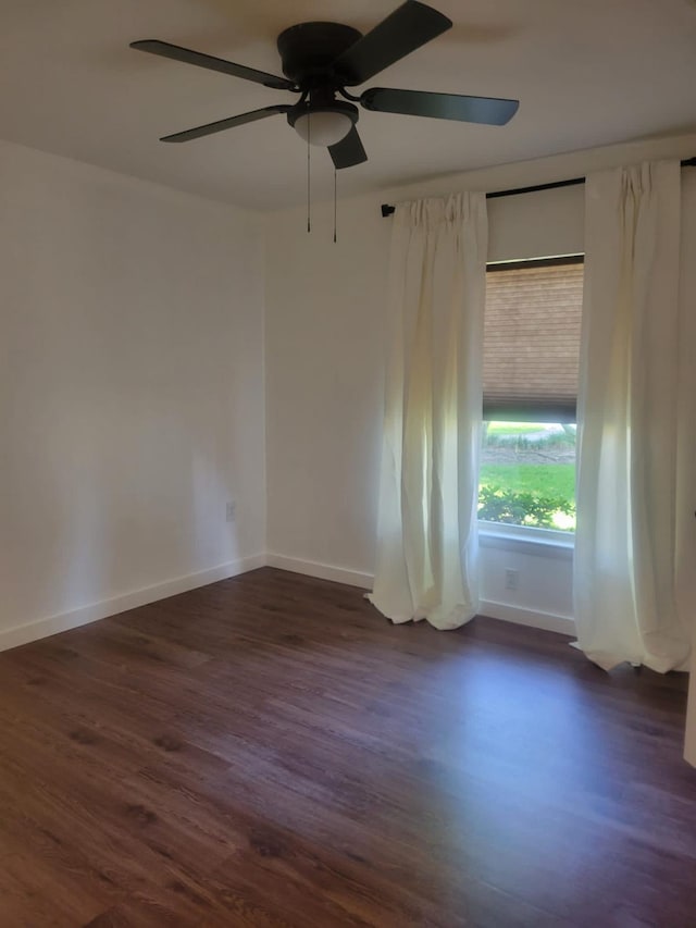 empty room with dark wood-style floors, baseboards, and a ceiling fan