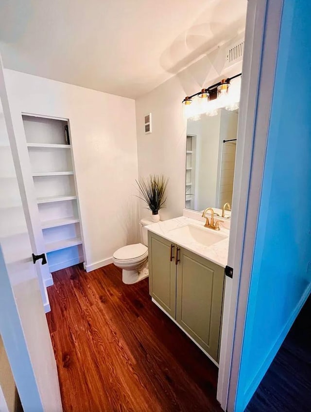 bathroom with toilet, wood finished floors, visible vents, vanity, and baseboards