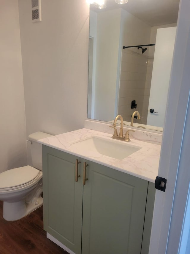 bathroom featuring toilet, wood finished floors, visible vents, vanity, and a shower