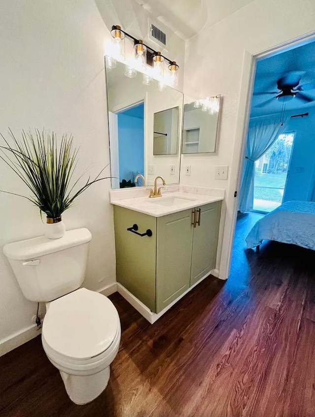 half bathroom with vanity, toilet, and wood finished floors