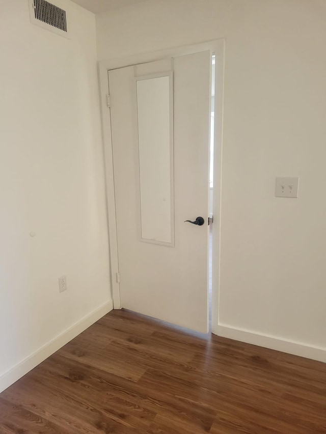 unfurnished room featuring baseboards, visible vents, and dark wood finished floors