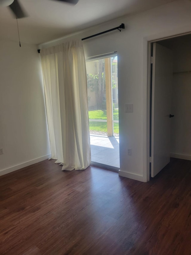 empty room with baseboards and dark wood-style flooring