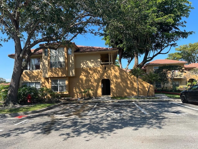 view of front of house featuring uncovered parking, a tile roof, and stucco siding