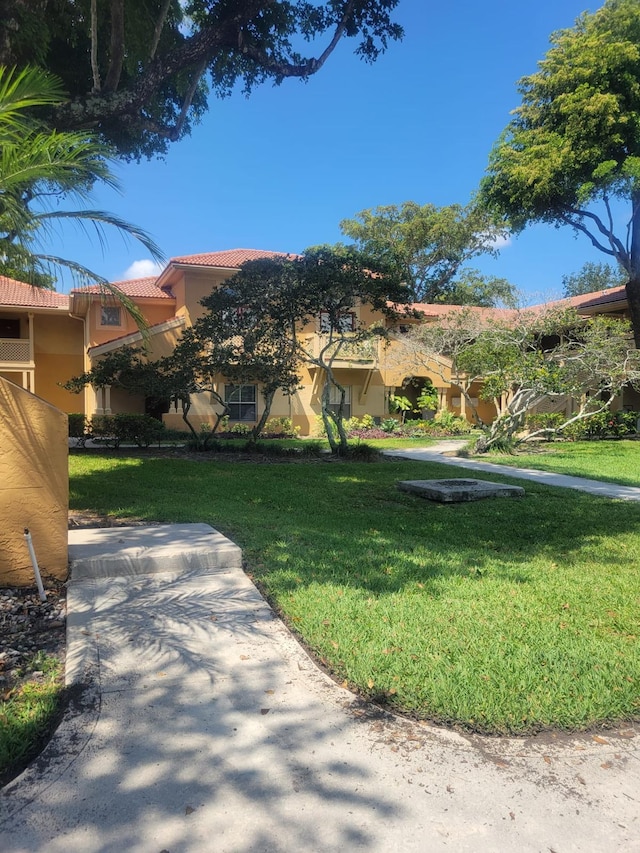 view of front of house with a tile roof, a front lawn, and stucco siding