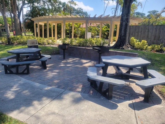 view of property's community featuring outdoor dining area, a patio area, fence, and a pergola