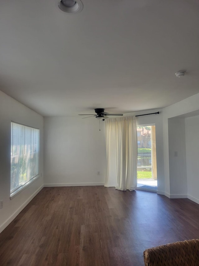 empty room featuring dark wood-type flooring, baseboards, and a ceiling fan