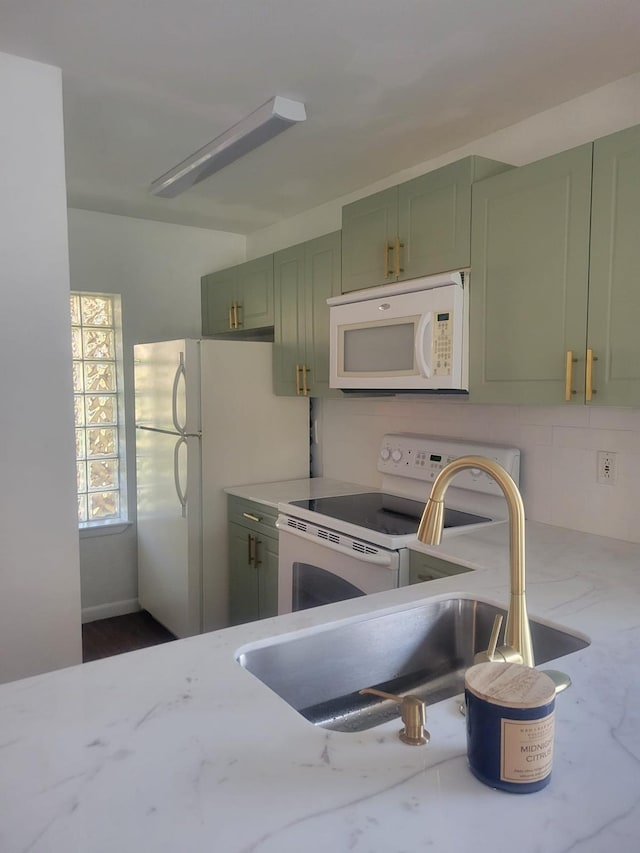 kitchen featuring light stone counters, white appliances, a sink, decorative backsplash, and green cabinetry