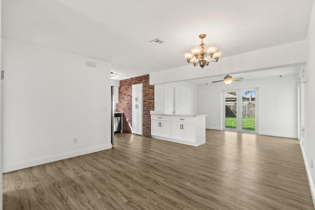 unfurnished living room featuring visible vents, baseboards, wood finished floors, and ceiling fan with notable chandelier