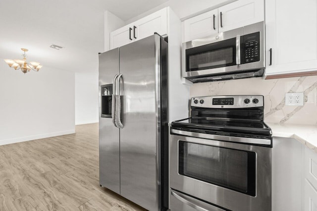 kitchen with appliances with stainless steel finishes, white cabinetry, light wood-style flooring, and decorative backsplash