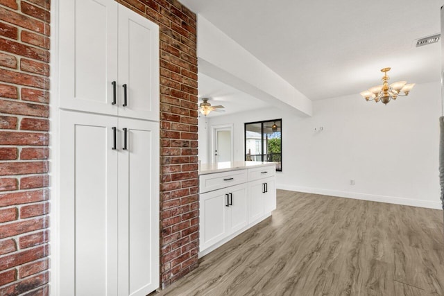 kitchen with ceiling fan with notable chandelier, baseboards, white cabinets, light countertops, and light wood finished floors