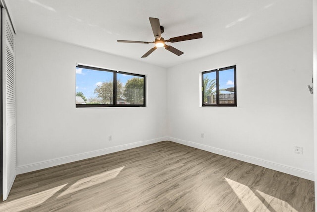 unfurnished bedroom featuring multiple windows, baseboards, a closet, and wood finished floors