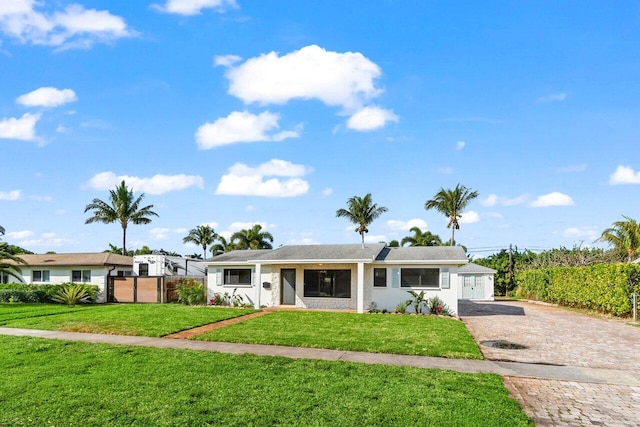 ranch-style home with a front lawn, decorative driveway, and fence