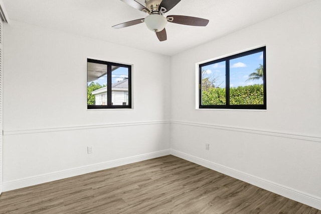 empty room with a healthy amount of sunlight, baseboards, and wood finished floors