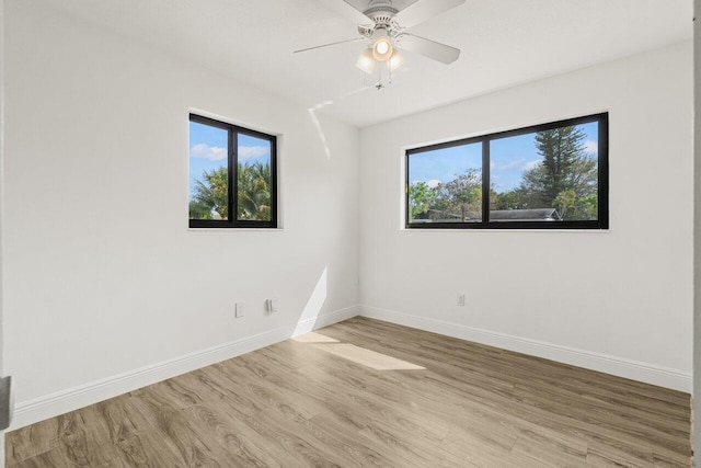 spare room featuring wood finished floors, a wealth of natural light, and baseboards