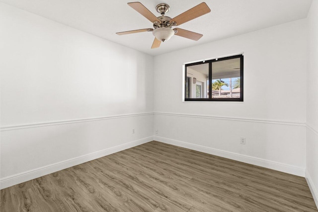 empty room with a ceiling fan, baseboards, and wood finished floors