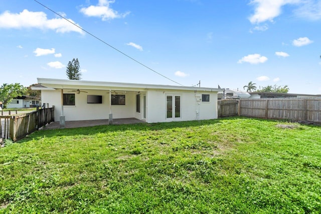 back of house with a yard, a fenced backyard, ceiling fan, and stucco siding