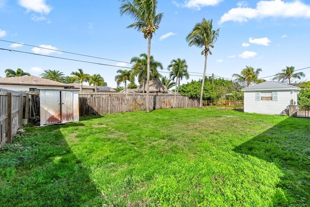 view of yard with a storage shed, a fenced backyard, and an outdoor structure