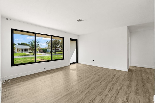 spare room featuring visible vents, light wood-style flooring, and baseboards