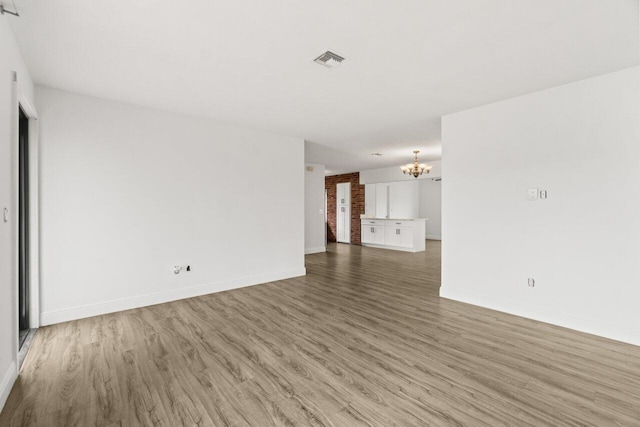 unfurnished living room with light wood-style floors, visible vents, a notable chandelier, and baseboards