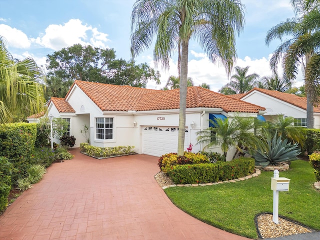 mediterranean / spanish house featuring an attached garage, stucco siding, decorative driveway, and a tiled roof