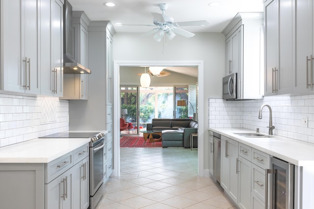 kitchen with beverage cooler, appliances with stainless steel finishes, gray cabinets, light countertops, and a sink