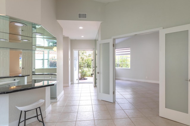 interior space featuring light tile patterned floors, baseboards, visible vents, dark countertops, and recessed lighting