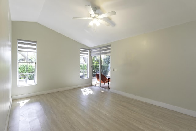 spare room with lofted ceiling, light wood-type flooring, plenty of natural light, and baseboards