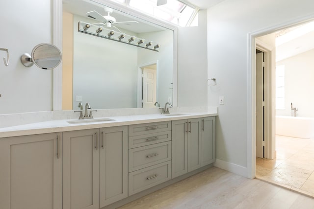 bathroom with ceiling fan, wood finished floors, a sink, and double vanity