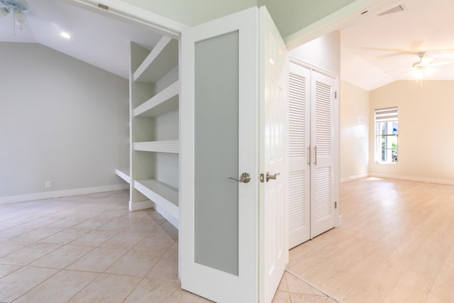 hall featuring built in features, light tile patterned floors, lofted ceiling, visible vents, and baseboards