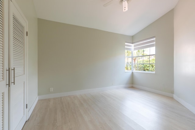 unfurnished bedroom featuring baseboards, a ceiling fan, lofted ceiling, light wood-style floors, and a closet