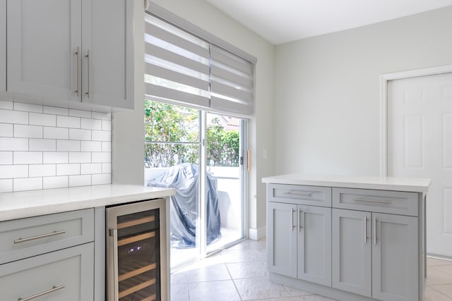 kitchen featuring wine cooler, backsplash, gray cabinetry, and light tile patterned floors