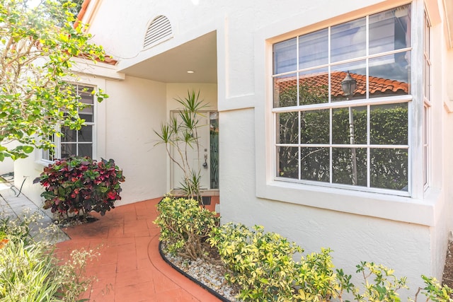 doorway to property featuring a patio, visible vents, and stucco siding