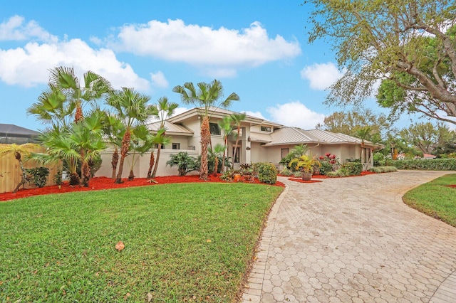 view of front of home featuring stucco siding, fence, decorative driveway, and a front yard