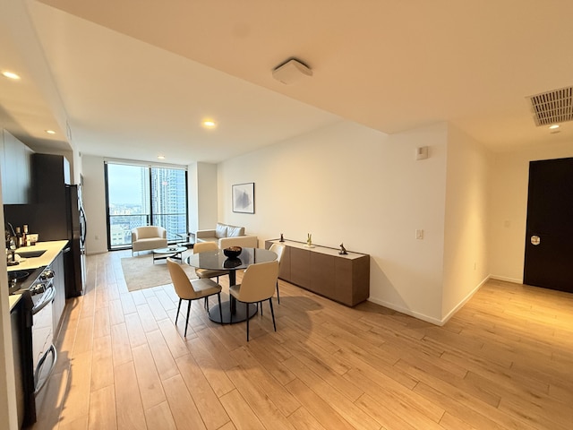 dining room with recessed lighting, visible vents, baseboards, light wood finished floors, and a wall of windows