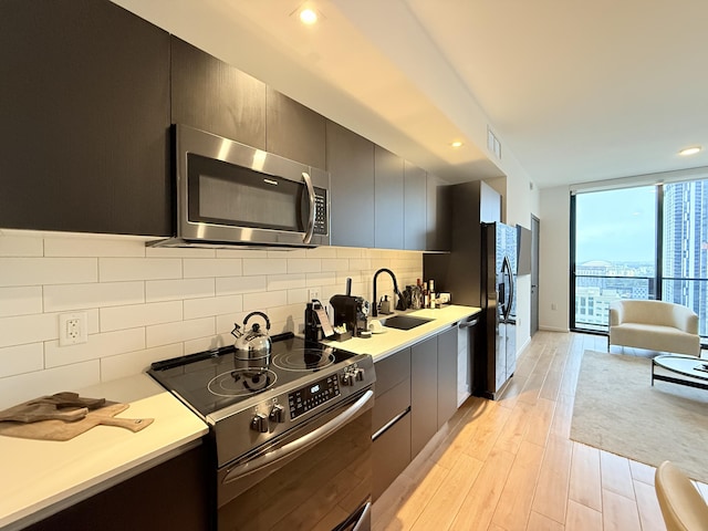 kitchen with stainless steel appliances, light countertops, a sink, modern cabinets, and a wall of windows