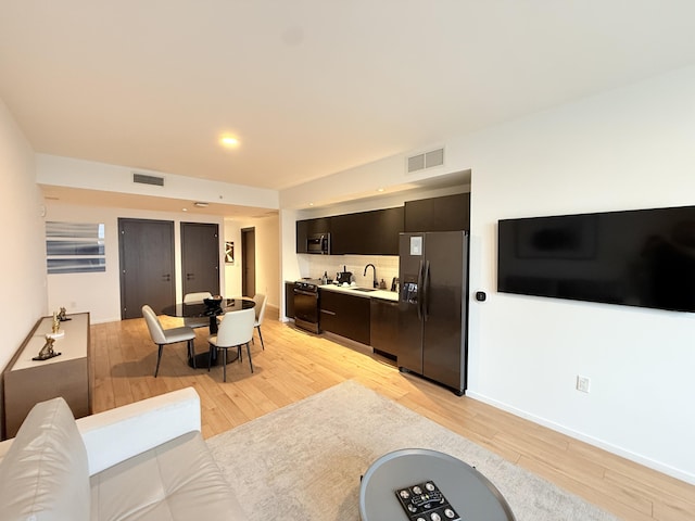 living room with baseboards, visible vents, and light wood-style floors