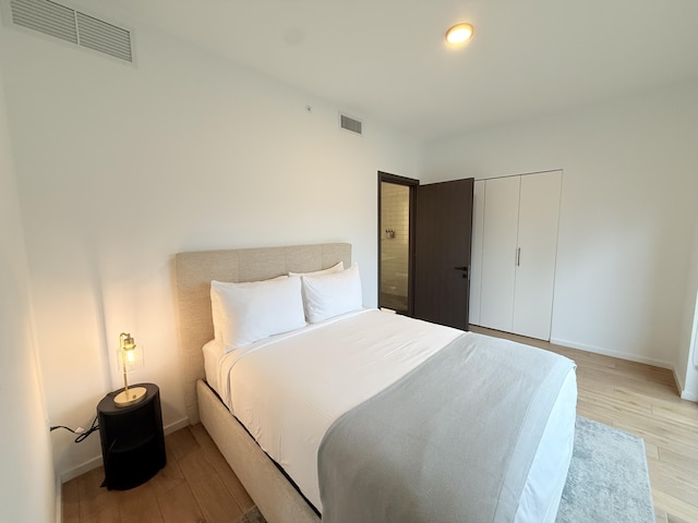 bedroom featuring light wood-type flooring, baseboards, and visible vents