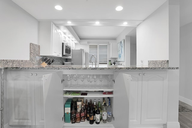 kitchen featuring white cabinetry, light stone counters, stainless steel appliances, and backsplash