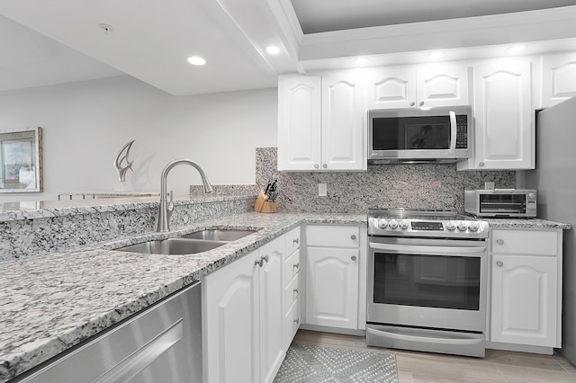 kitchen with stainless steel appliances, white cabinets, a sink, and decorative backsplash