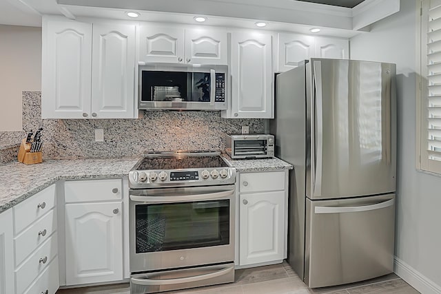 kitchen with light stone counters, appliances with stainless steel finishes, and white cabinetry