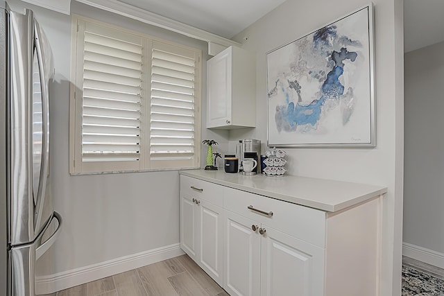 interior space with light wood-type flooring, freestanding refrigerator, and baseboards