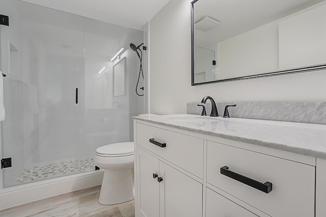 full bathroom featuring a stall shower, vanity, toilet, and wood finished floors