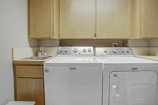 clothes washing area with cabinet space, separate washer and dryer, and a sink