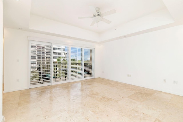 empty room with a tray ceiling and a ceiling fan