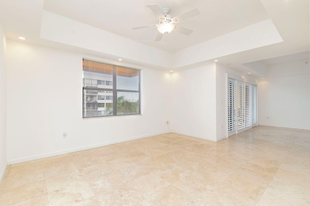 spare room featuring a ceiling fan, a tray ceiling, baseboards, and recessed lighting