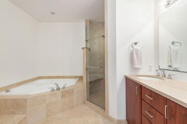 bathroom with a stall shower, tile patterned flooring, a garden tub, and vanity