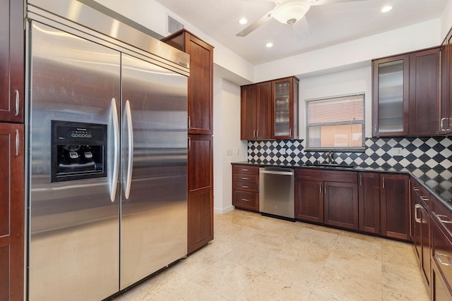 kitchen with stainless steel appliances, dark countertops, a sink, and decorative backsplash