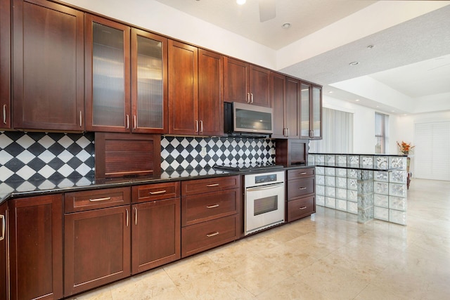 kitchen with tasteful backsplash, dark countertops, cooktop, stainless steel microwave, and wall oven