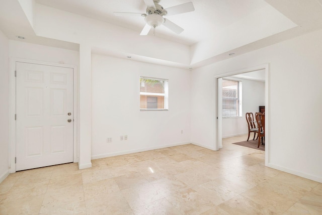 unfurnished room featuring baseboards, a raised ceiling, and a ceiling fan